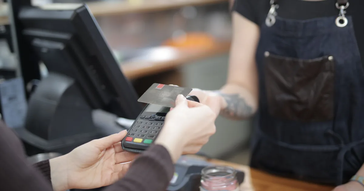 Cliente y cajero durante una transacción con tarjeta en el mesón de una tienda