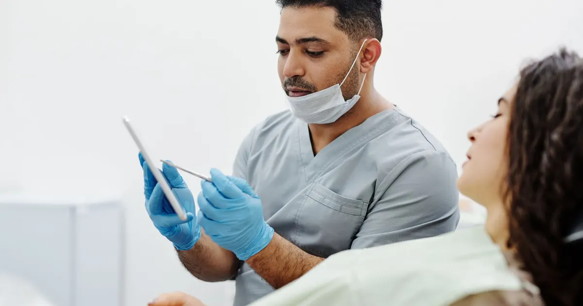 Profesional de salud usa una tablet para consultar información junto a un paciente en una clínica