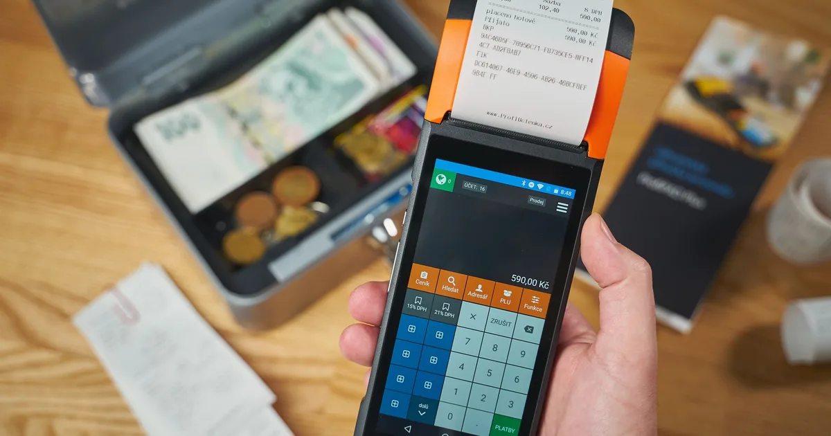 Primer plano de un terminal de pago portátil imprimiendo un comprobante, con billetes y monedas junto a él