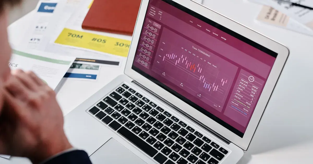 Persona revisando un panel de analítica de datos en la pantalla de un computador portátil en una oficina