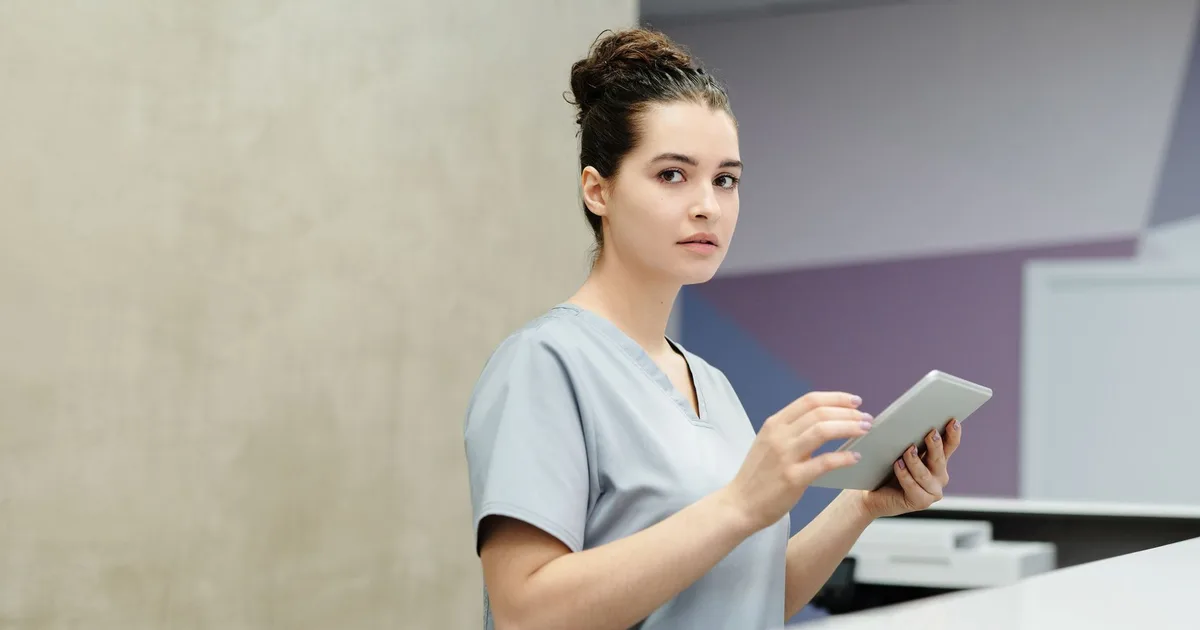 Recepcionista revisa una tablet en el mostrador de recepción de una oficina moderna