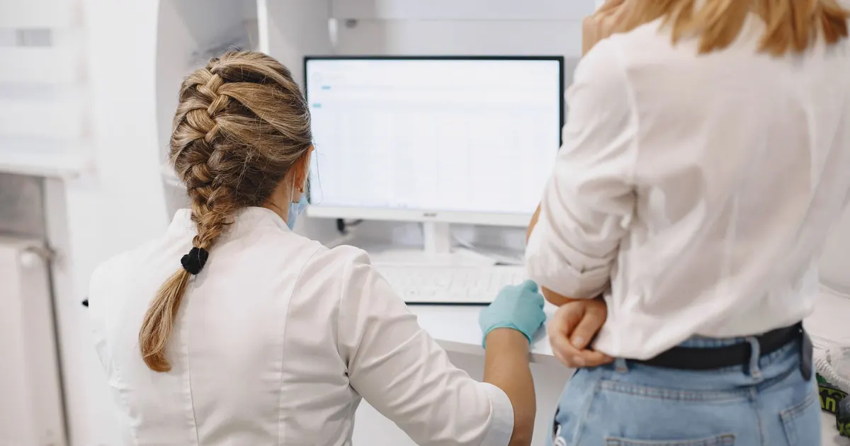 Dos profesionales de la salud revisan datos en una pantalla de computador en un entorno clínico