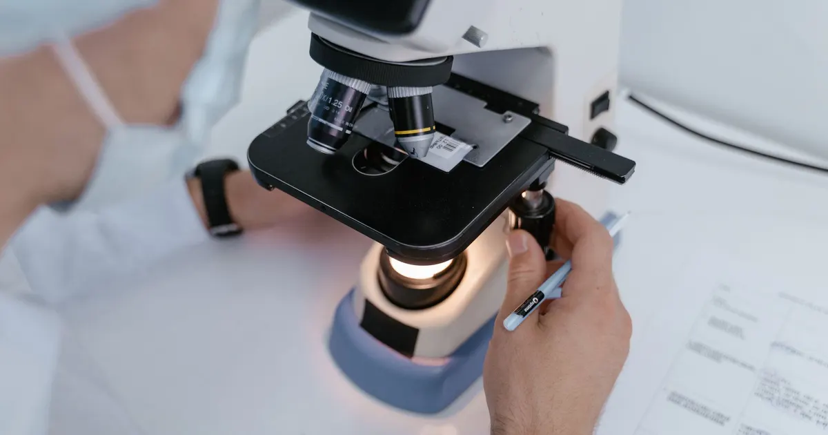 Científico examina una muestra bajo el microscopio en un laboratorio clínico