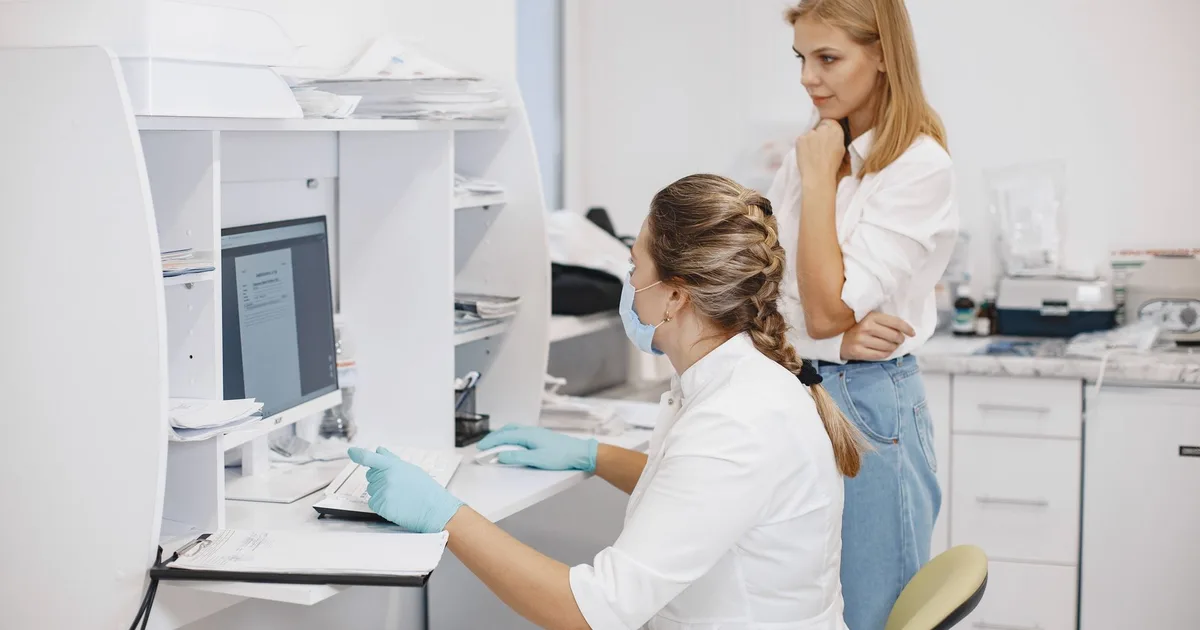 Dos profesionales de salud revisan resultados en la pantalla de una computadora en una oficina clínica.