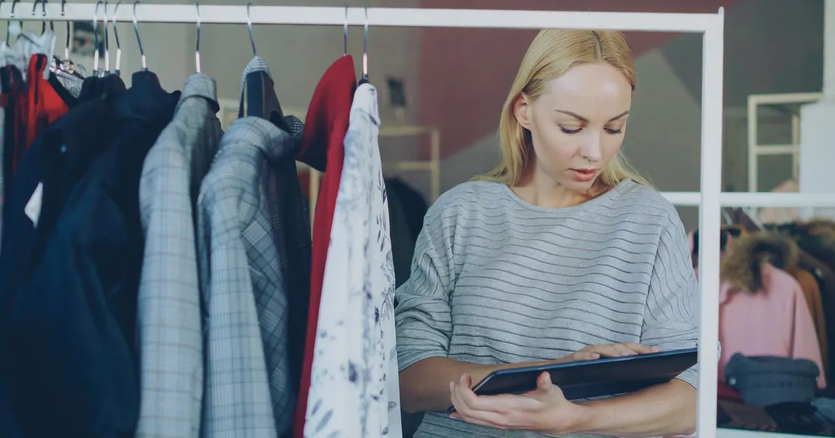 Empleada de tienda revisa inventario con una tablet frente a estantes de productos