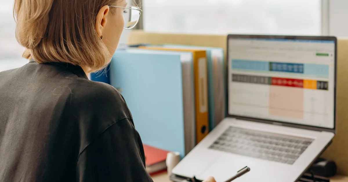 Mujer profesional revisando datos en una laptop en una oficina moderna