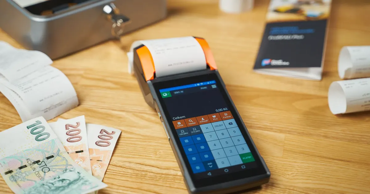 Terminal de pago digital sobre un escritorio de madera junto a efectivo y boletas