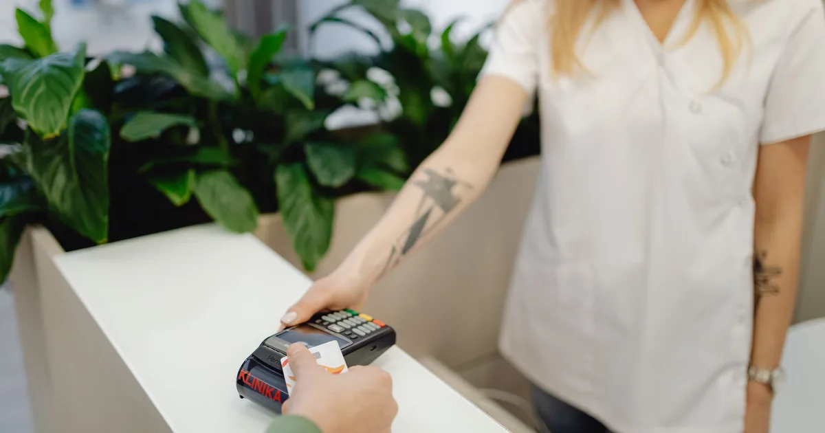 Personal de clínica con tatuajes ayuda a procesar un pago con tarjeta de crédito
