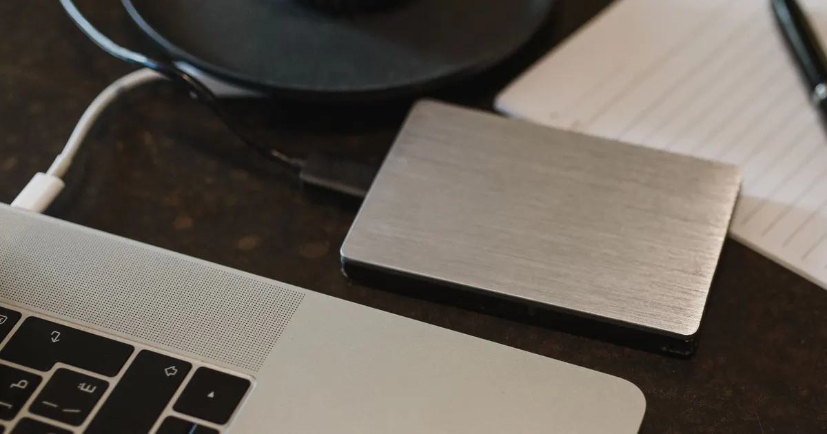 Primer plano de un disco duro externo conectado con un cable USB a un laptop sobre un escritorio