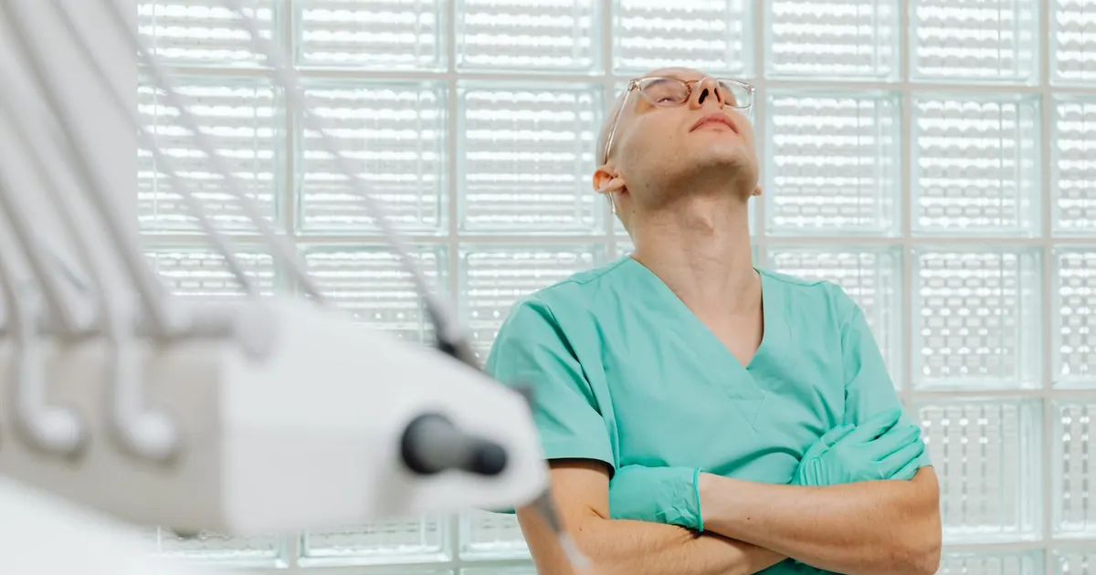 Trabajador de salud con uniforme clínico luce exhausto en una sala de examinación médica