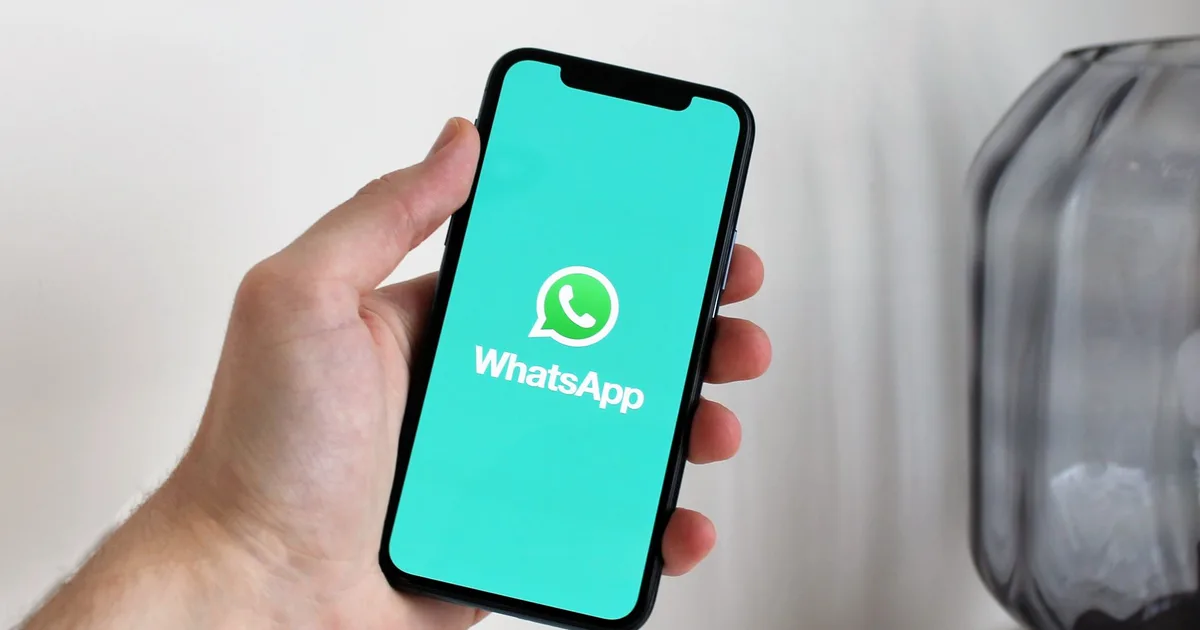 Primer plano de una mano sosteniendo un smartphone con la pantalla de WhatsApp abierta